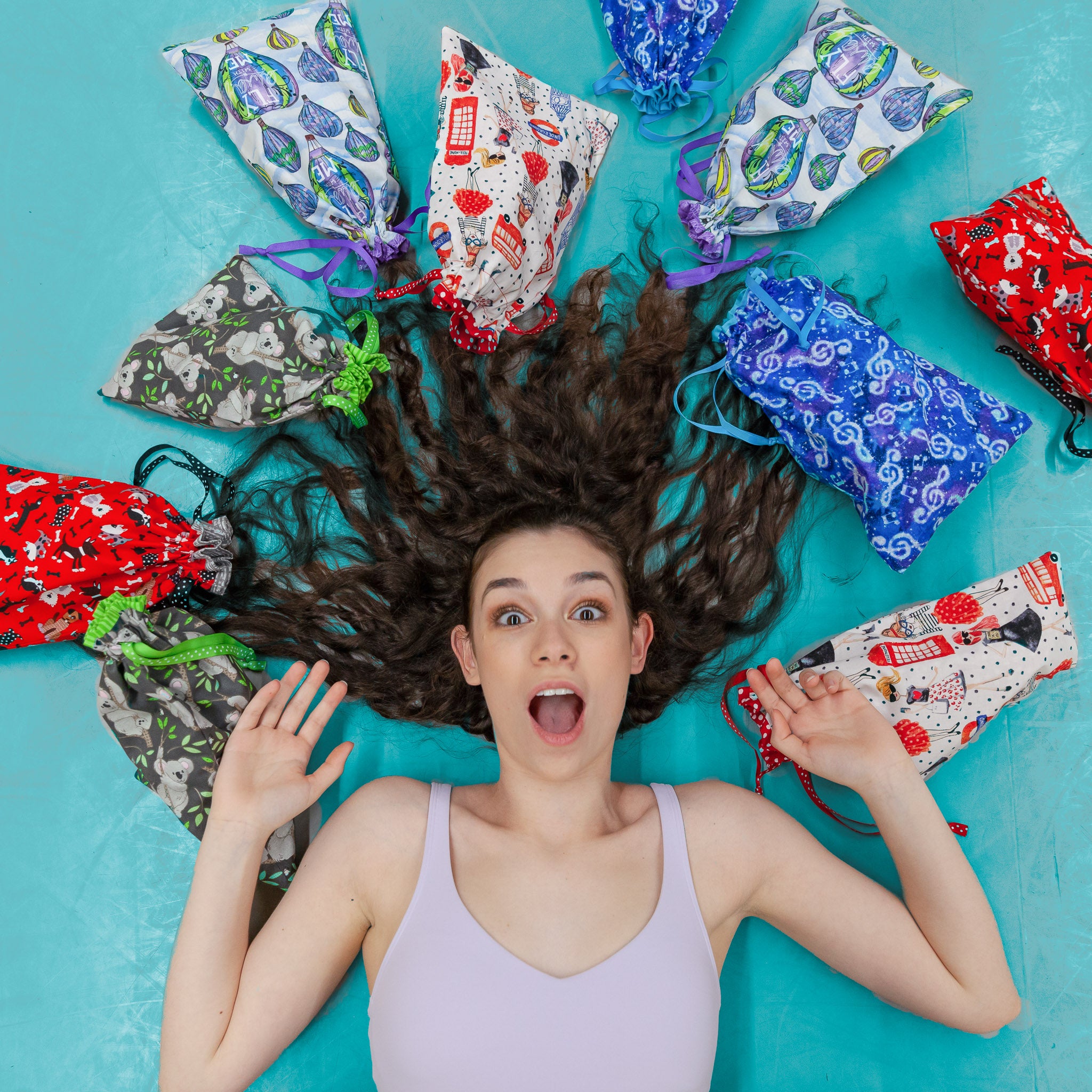 A surprised girl with long hair spread around her head surrounded by a variety of colorful fabric shoe bags