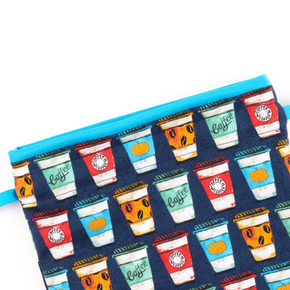 Close up of travel shoe bag with red, blue. and orange to-go coffee cups on the fabric, and turquoise lining