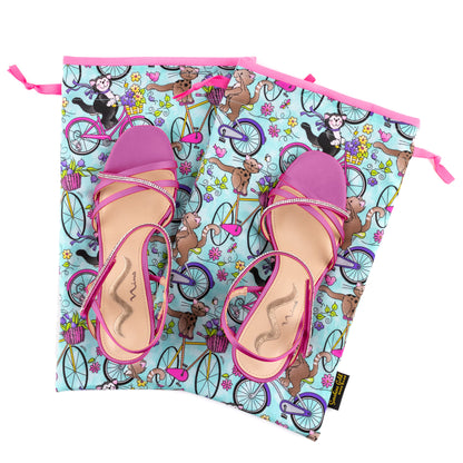 Two pink high-heeled sandals on top of two fabric shoe bags for travel